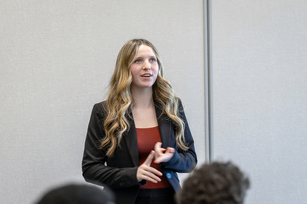 female student standing and talking while counting out her point on her finger