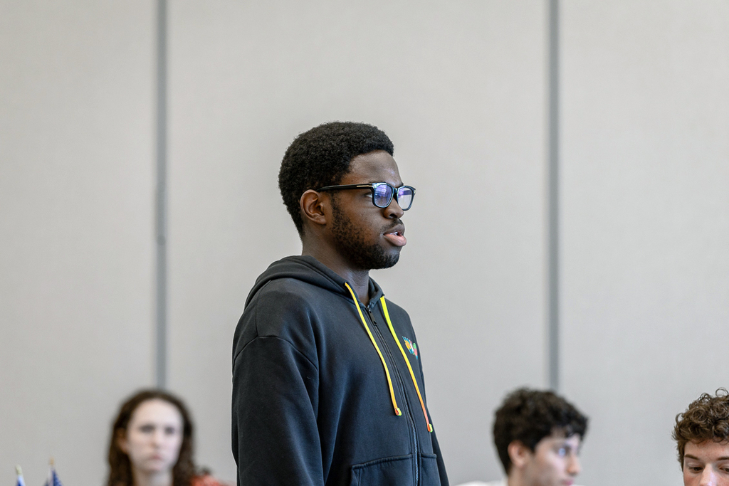 male student standing and talking to the group. 