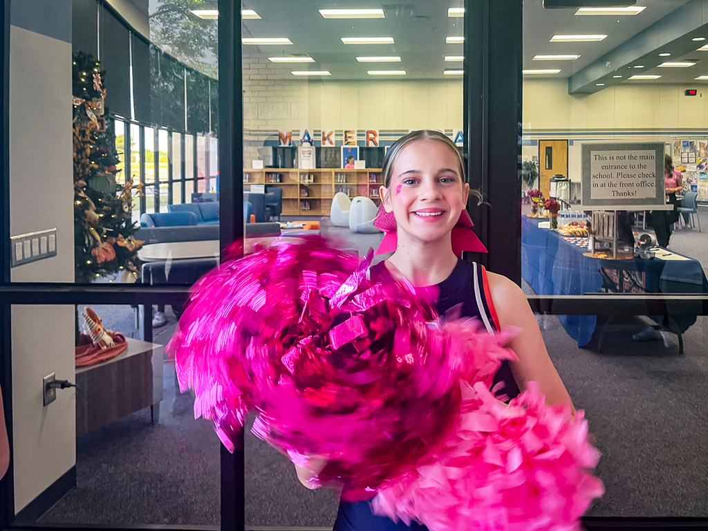 cheerleader smiling at camera while shaking pink poms