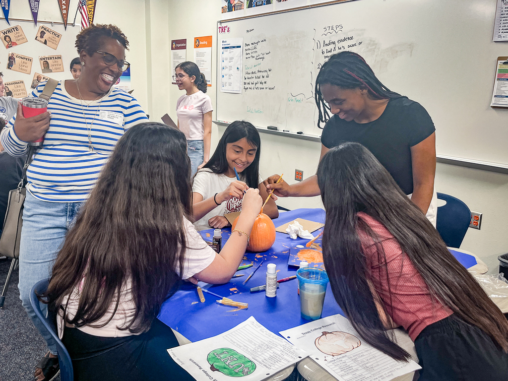 guest talking and laughing with girls who are painting a pumpkin