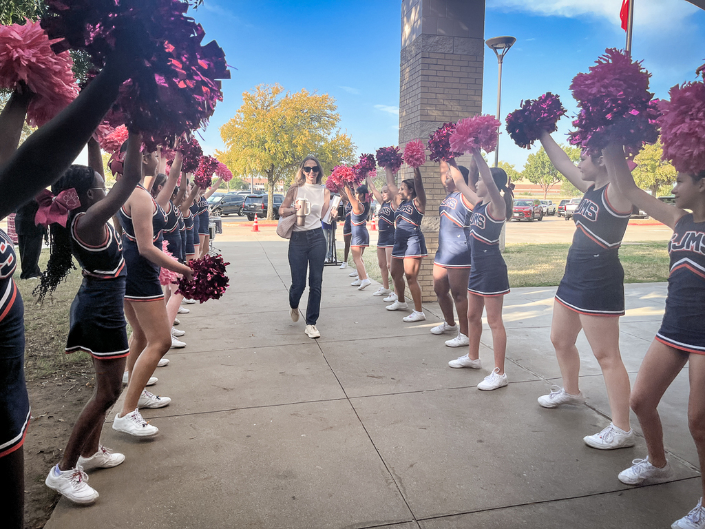 female guest arriving as cheerleaders line the walk with poms raised over their heads