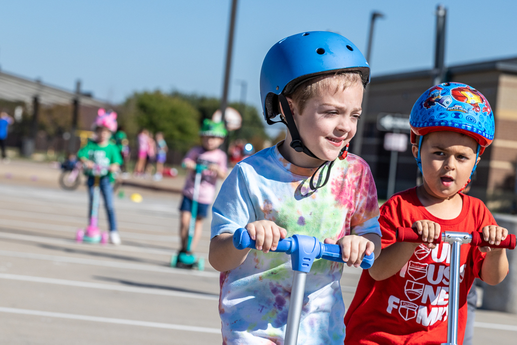 two boys on scooters riding past camera