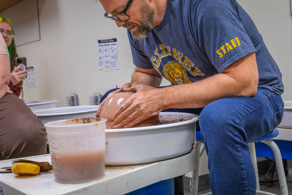 male teacher demonstrating working on clay on pottery wheel
