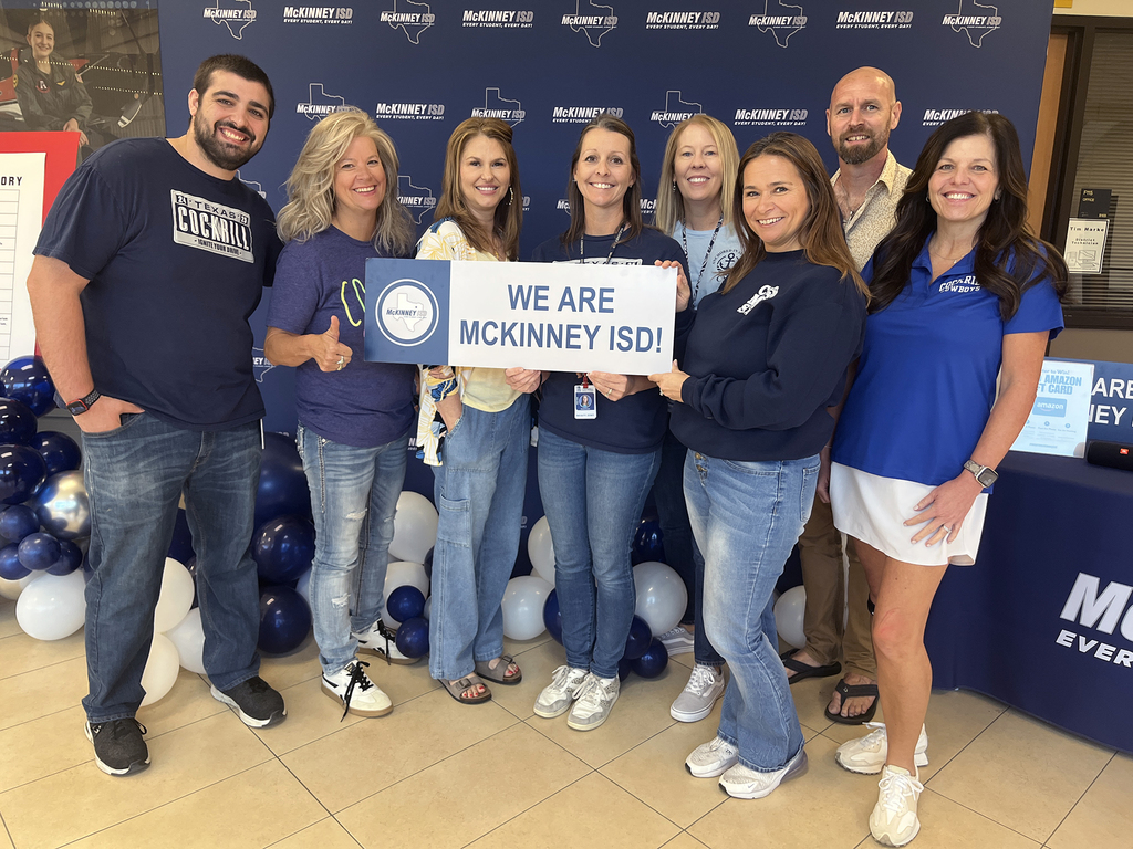 group of teachers in front of logo backdrop holding we are McKinney ISD sign