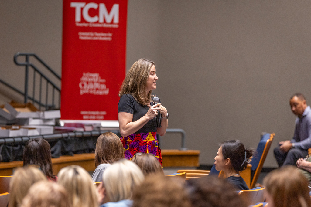 female speaker with microphone at the front of the room speaking