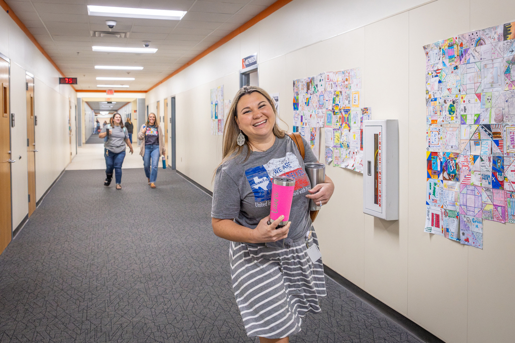female teacher smiling and walking down the hall