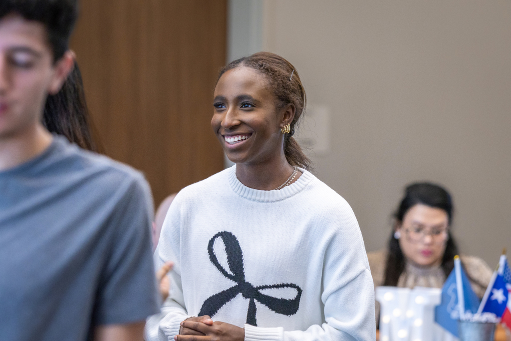 female student standing and smiling as she talks with another student
