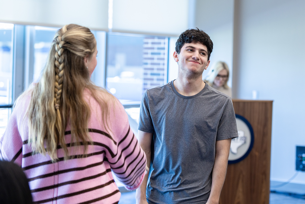 male student reacting with a smile as he loses in a game of rock paper scissors