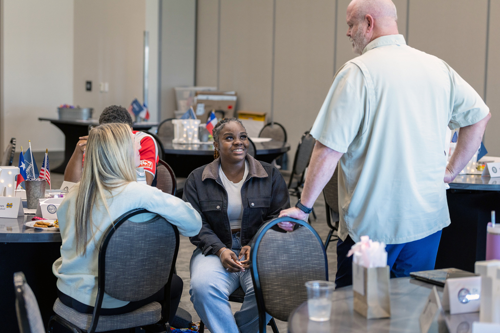 Shawn Pratt standing and talking to two female students who are seated