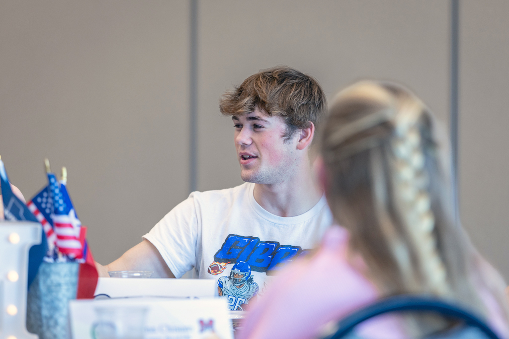 male student seated and talking with people at his table