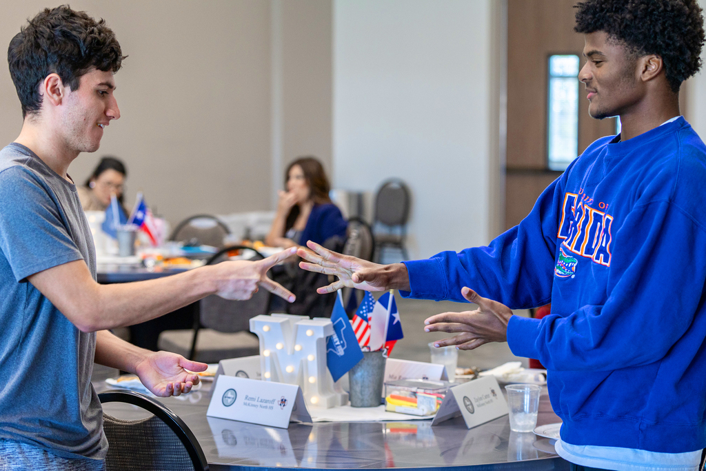 two male students standing and playing rock paper scissors