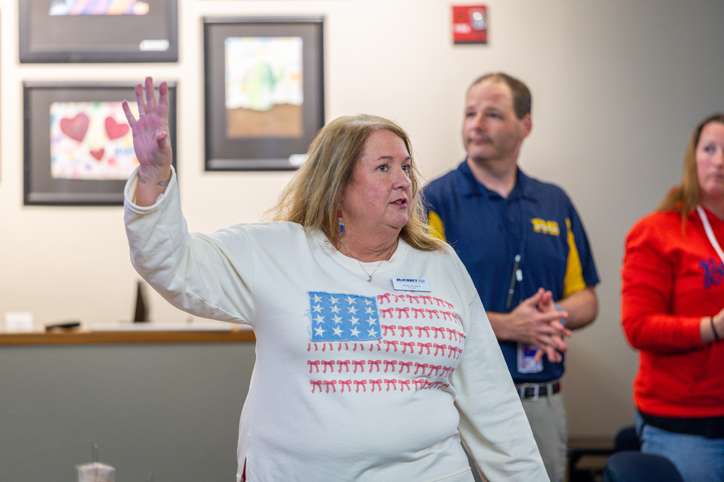 principal Holly Rogers talks to the group as she gestures toward overhead screen