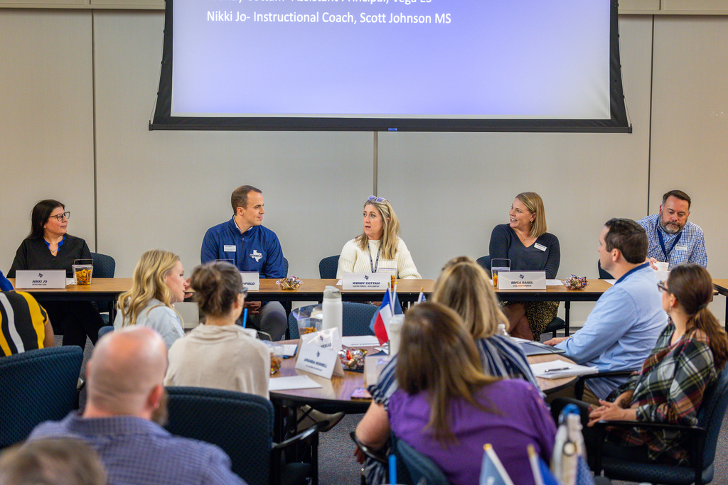 wide view of the panel seated at table at front of the room