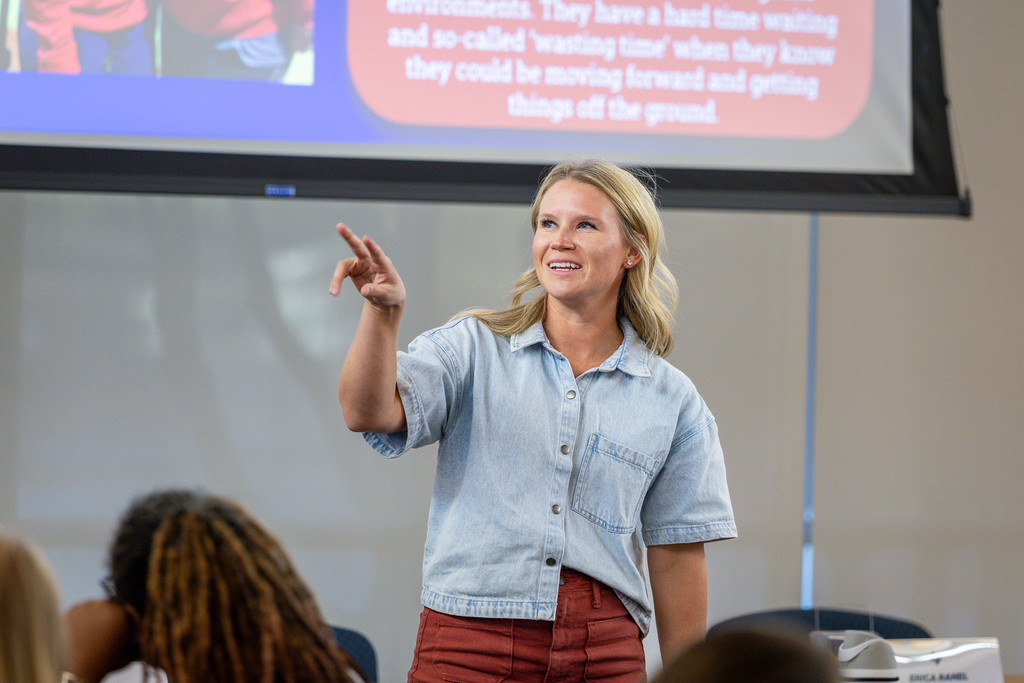 female participant looking toward screen and smiling and pointing at it