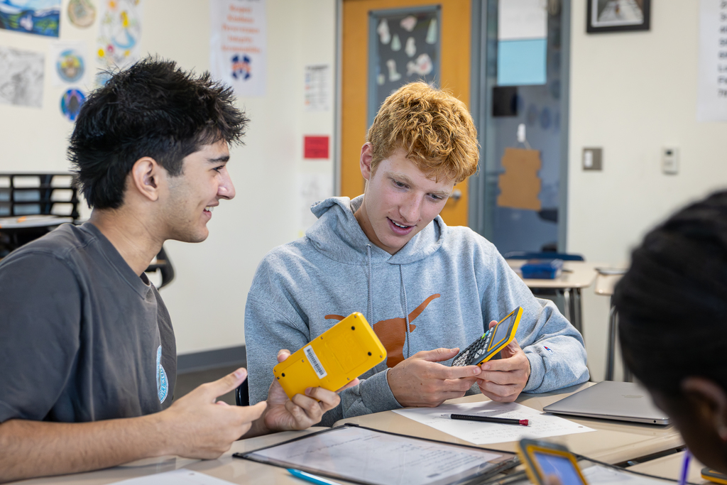 two male students smiling and looking at their calculations