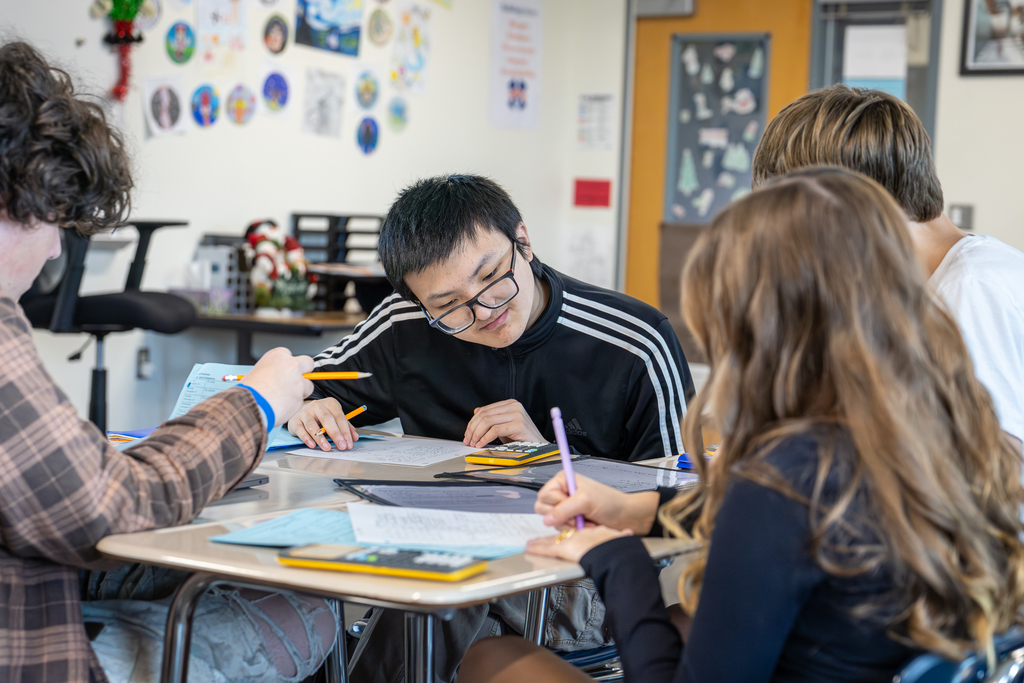 male student looking at his calculator as he works