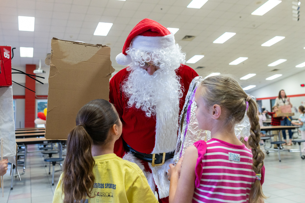 man in santa suit talking with two girls before the parade