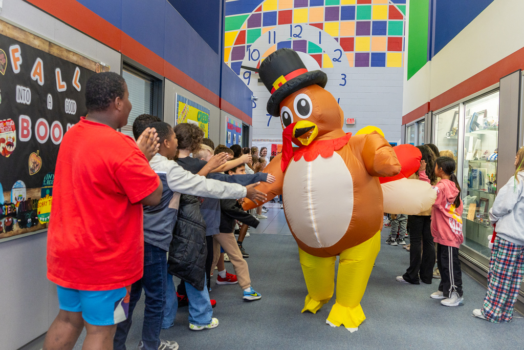 man in inflatable turkey suit high fiving students during parade