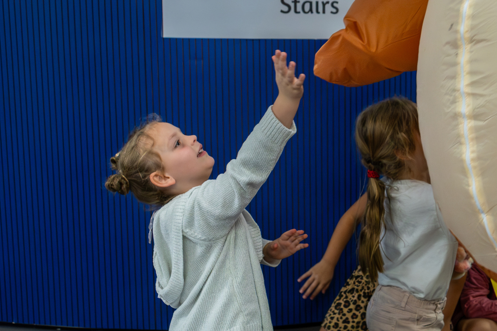 young girl reaching up excitedly to high five the turkey