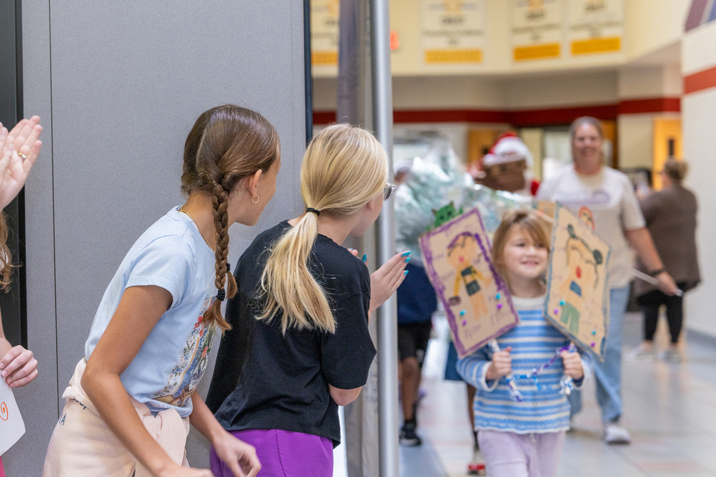 two girls looking around corner in anticipation as the parade approaches