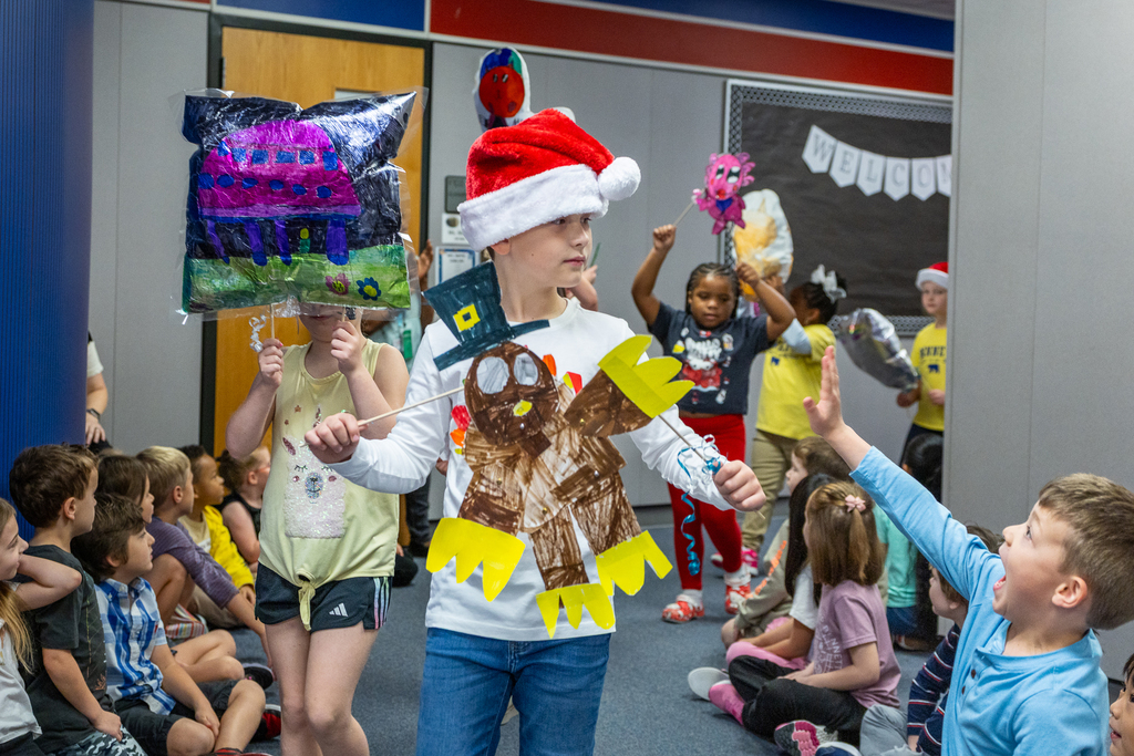 boy in parade holding his turkey display while a boy waves at him energetically