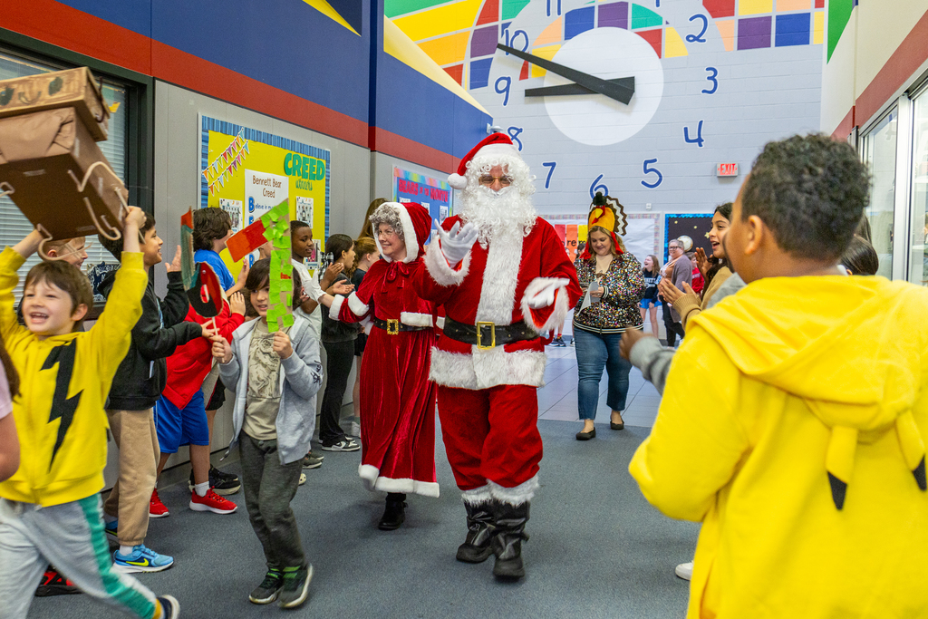 santa and mrs. claus walking on the parade route as santa gestures to a student