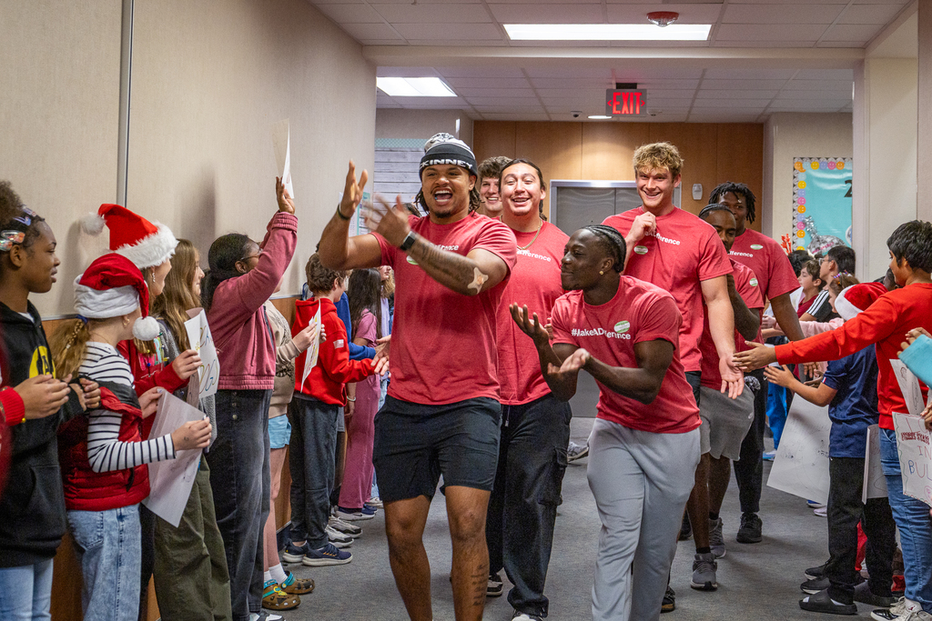 Ferris State players walking in and interacting with students who are cheering for them