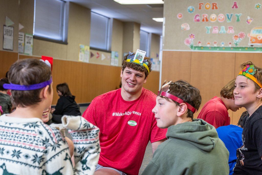 Ferris state player smiling at a student as he plays a game with a group