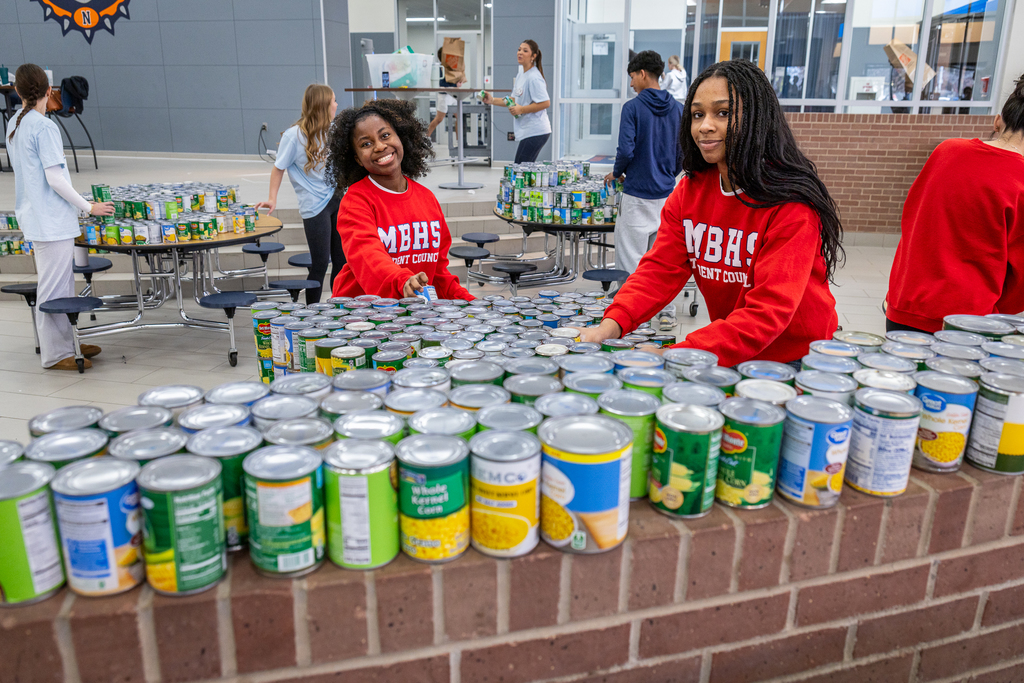 two girls from Boyd arranging a table filled with cans of corn