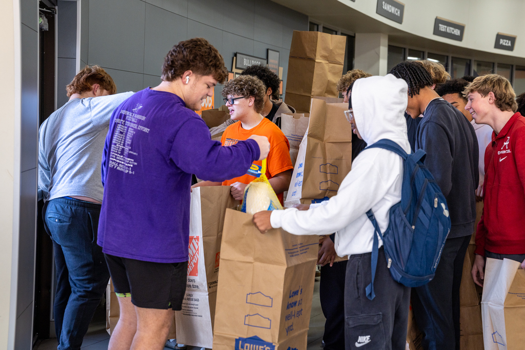 students waiting with large bags as other students load them with frozen turkeys
