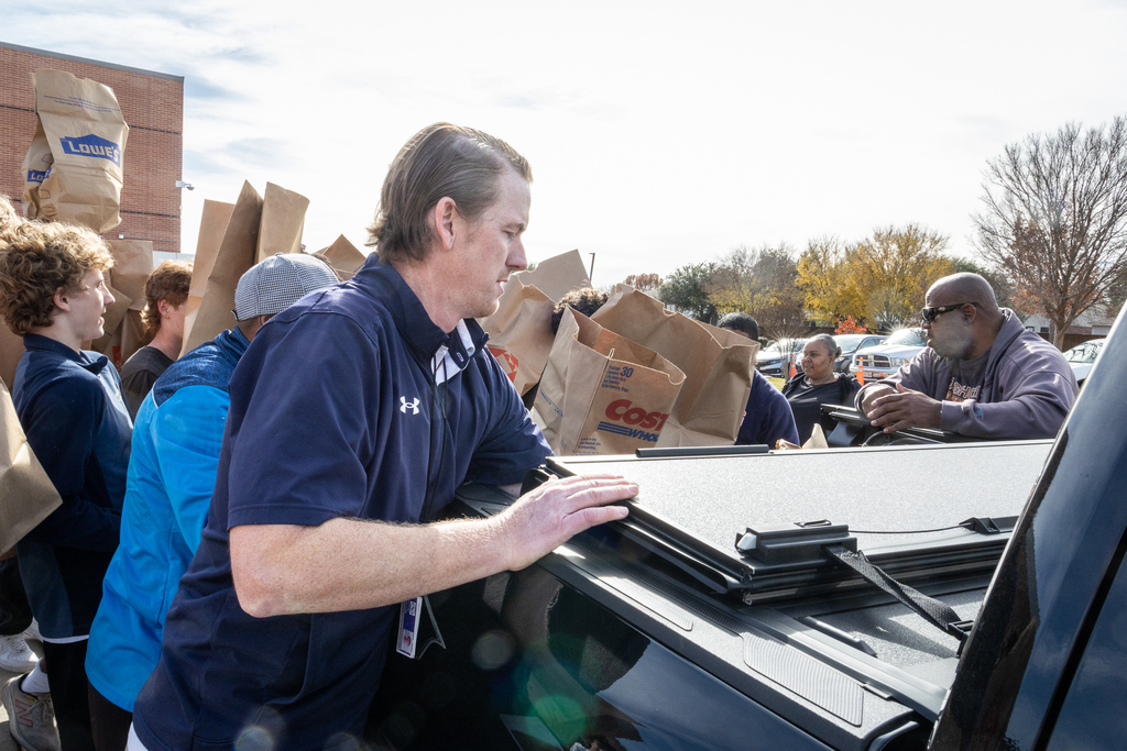 students and teachers loading filled bags into back of pickup truck