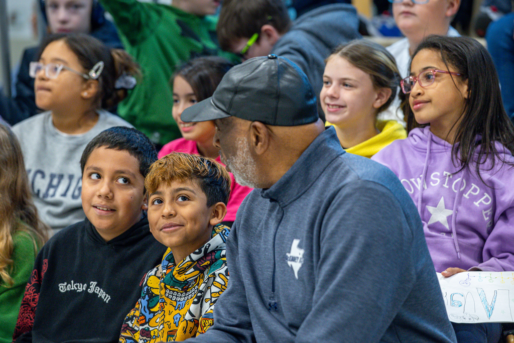 two male students sitting next to Larry Jagours look up at him and smile as he talks to them