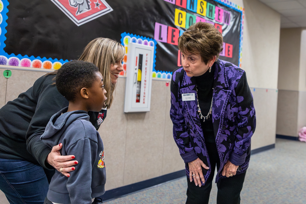 Sperry leaning down and talking to student in the hallway