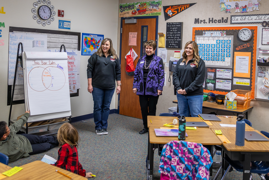 Sperry, Larriviere and Harvick standing at front of class and smiling at students