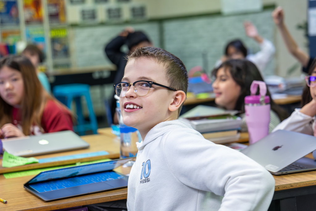 male student in class turning toward camera and smiling