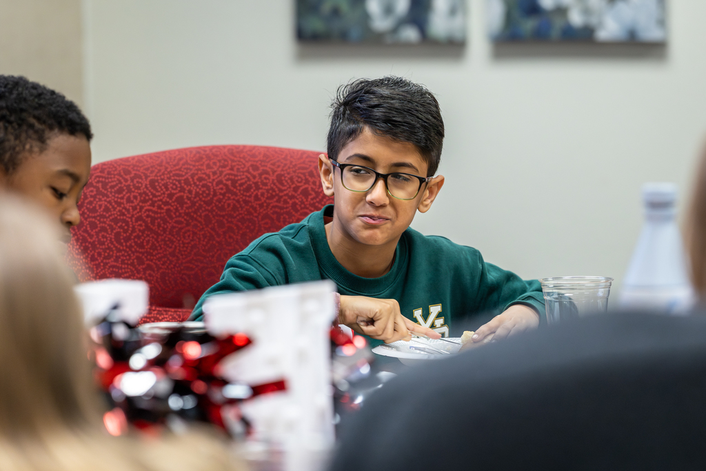 male student cutting food and looking at Sperry expressively during lunch