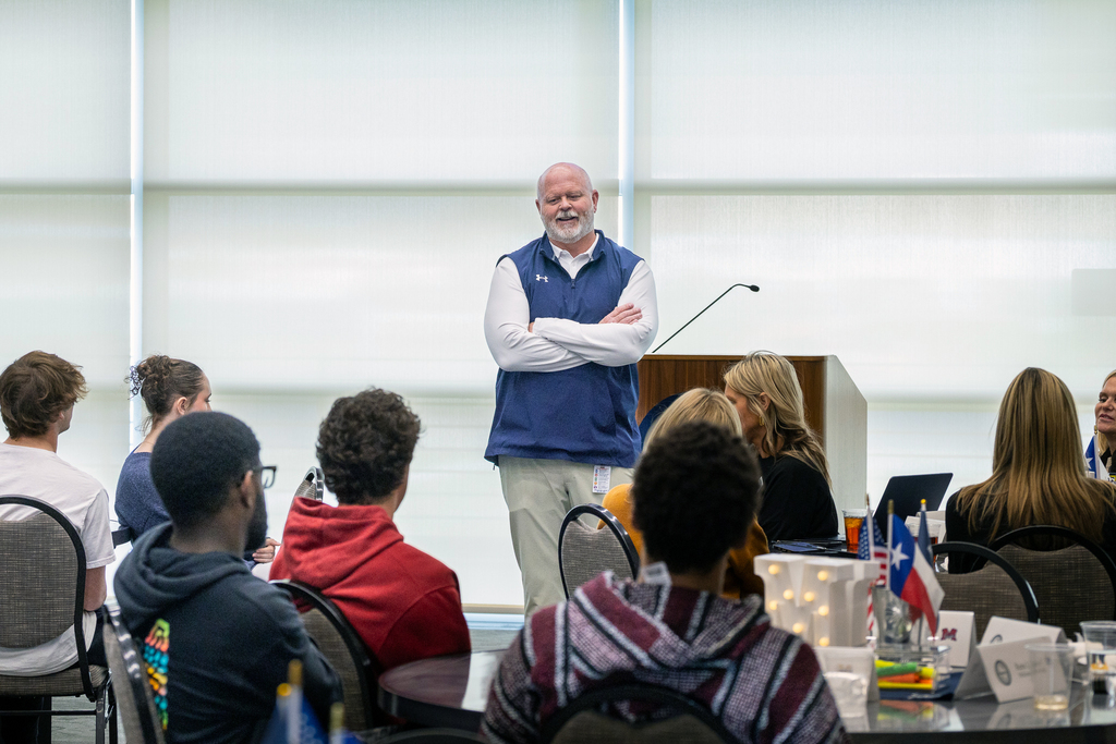 Shawn Pratt standing in front of the group and smiling as he dialogues with a student 