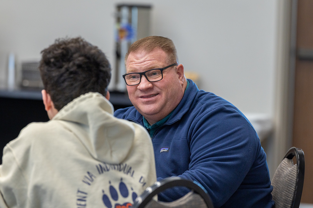 dennis womack talking with a student at a table 