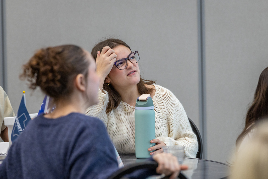 girl looking up toward screen while scratching her forehead with a quizzical expression