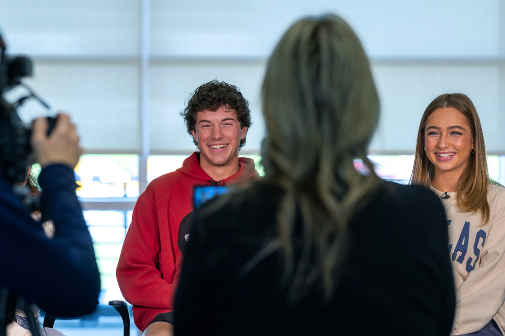 male and female student laughing as they talk before video interview