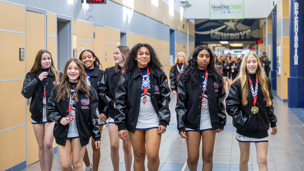 group of cheerleaders walking down the hall together with medals on