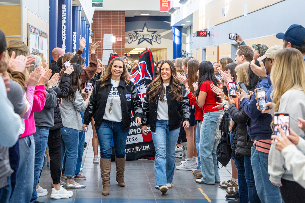 coaches walking through tunnel of parents cheering in hallway