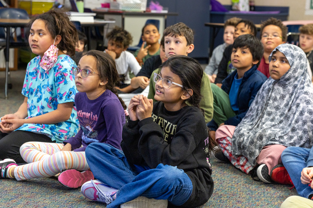 girl seated on floor listening to speaker with interest