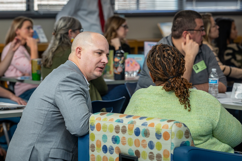 Jeff Banner kneeling and talking with participant who is seated