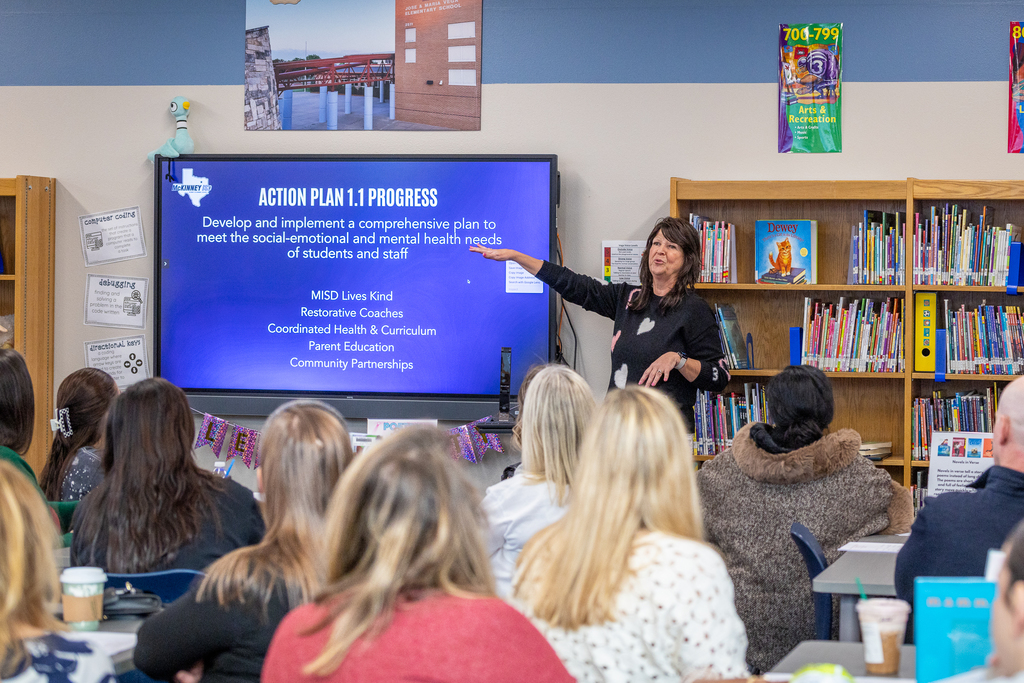 Errin French pointing at presentation board and speaking to the group