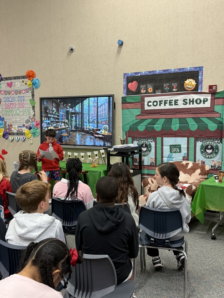 Image featuring a student reading to his peers during the 5th grade poetry cafe.