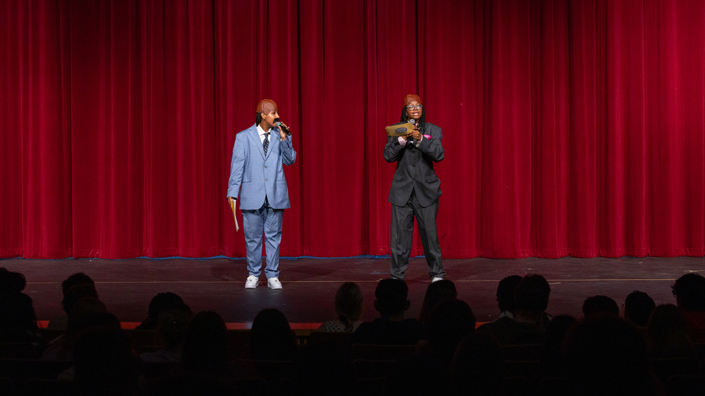 female performers onstage in Steve Harvey costumes