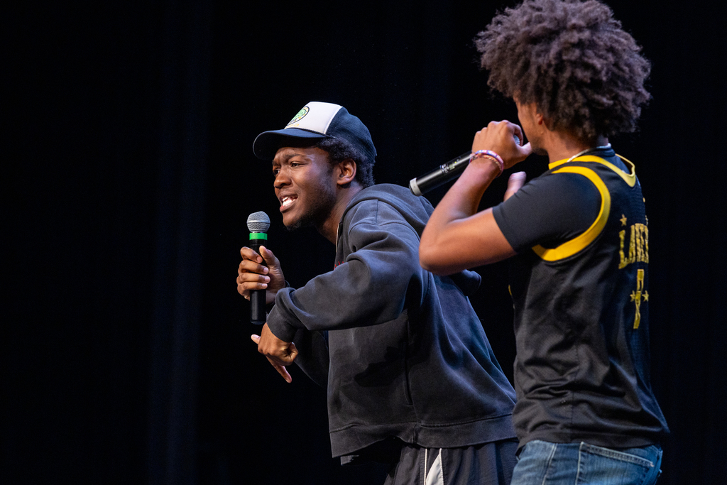 two male students on stage rapping together