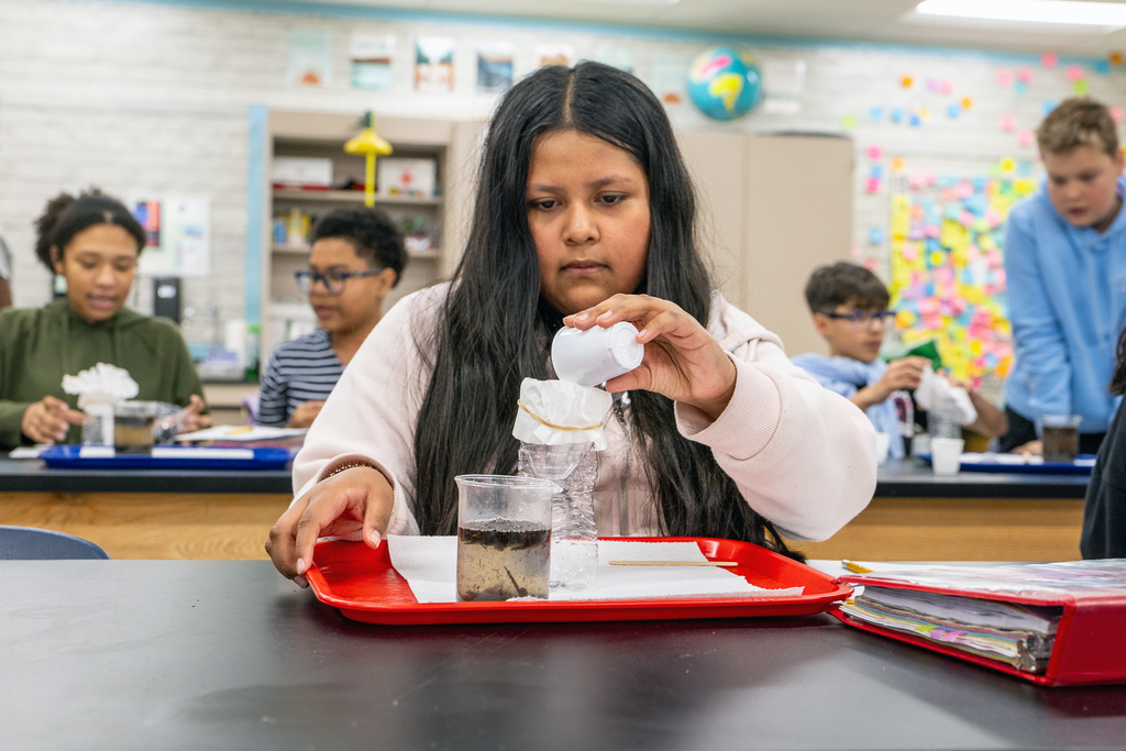 female student working on lab pouring water into bottle