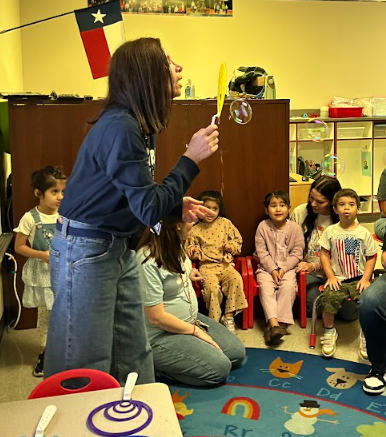 Mrs. Towber blows bubble out of a round wand to show that they always form spheres.